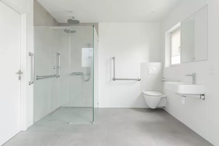 Modernes barrierefreies Badezimmer mit bodengleicher Dusche, Haltegriffen und unterfahrbarem Waschtisch